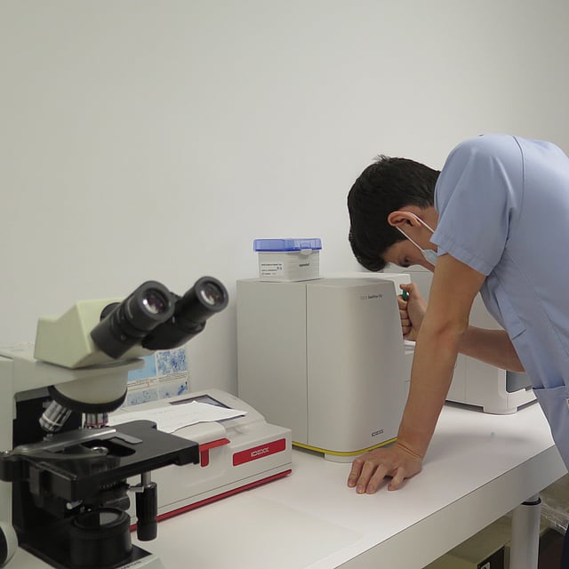 Una persona mirando un microscopio.