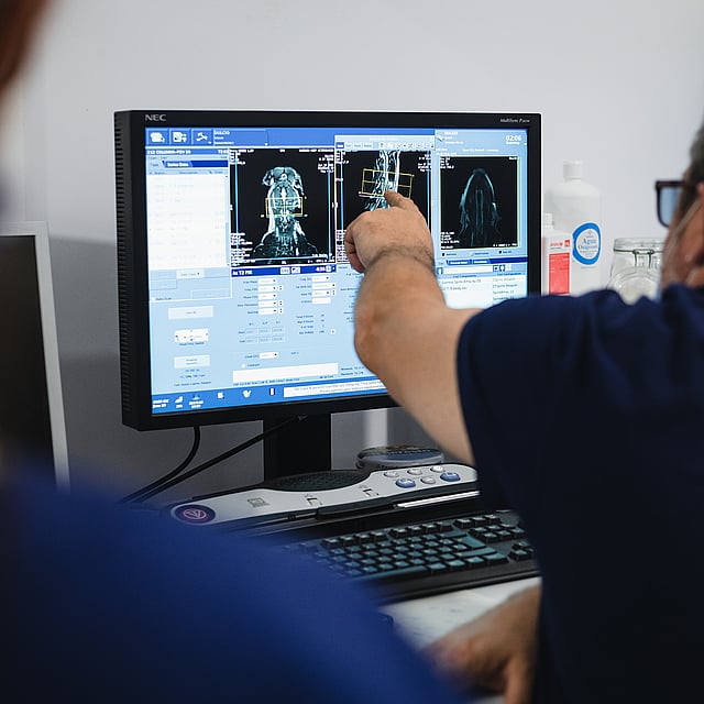 Una persona señalando la pantalla de una computadora.