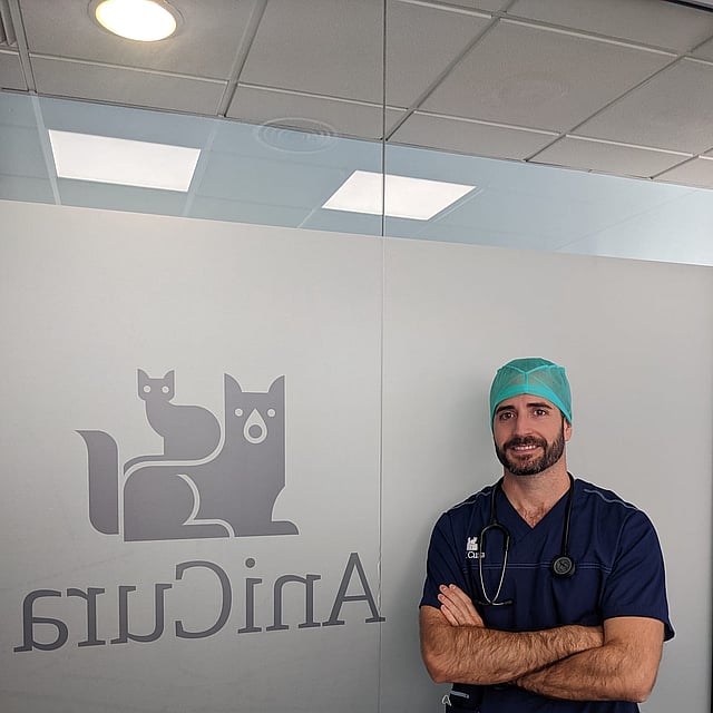 Una persona con bata y un estetoscopio de pie frente a una pared con un logotipo.