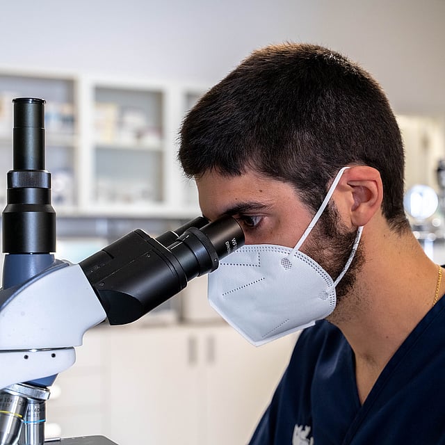 Una persona mirando a través de un microscopio.