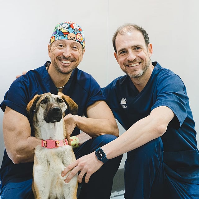 Dos hombres con bata sosteniendo a un perro.