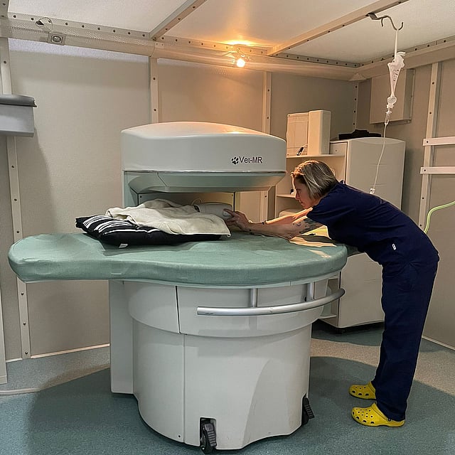Una persona con un uniforme azul de pie junto a una gran máquina médica.