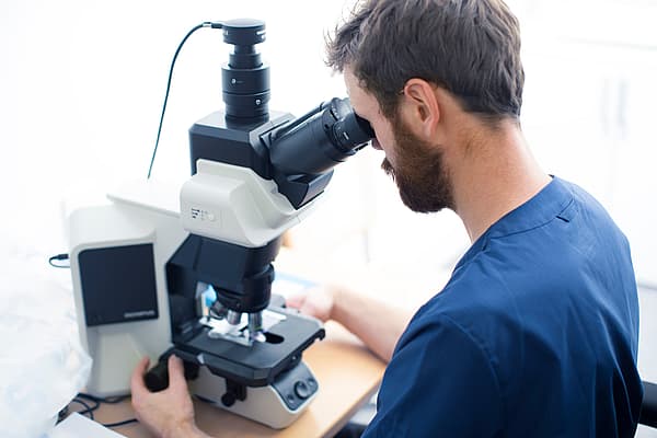 Una persona mirando a través de un microscopio.
