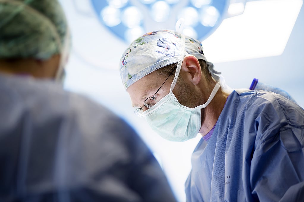 Un médico con bata quirúrgica y mascarilla.